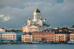 An illustrative photo of the Helsinki Cathedral with its green domes, set against a backdrop of colorful buildings