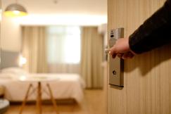 An illustrative photo of a modern hotel room with a neatly made bed, a desk, and a large window