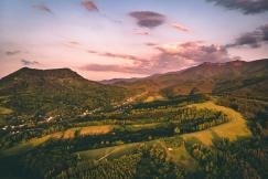 An illustrative photo of green trees and mountains under a cloudy sky.