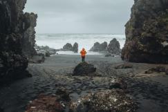 An illustrative photo of a person standing on a rocky beach next to the ocean
