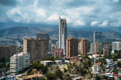 An illustrative photo of a city with tall buildings and mountains in the background.