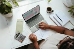 An illustrative photo of a person sitting at a table with a laptop 