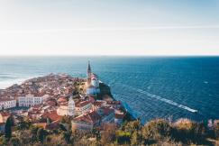 An illustrative photo of brown-roofed buildings near the sea in Piran, Slovenia