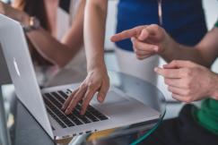 An illustrative photo of a person touching and pointing at a MacBook Pro