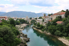 An illustrative photo of a river between coasts with houses and with mountains in the background