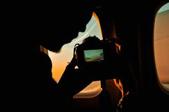 An illustrative photo of a person taking a picture of a plane window.