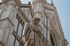 An illustrative photo of a statue of a man holding a book in front of a building