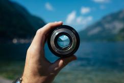 An illustrative photo of a person holding a camera lens