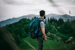 An illustrative photo of a man carrying his backpack overlooking the landscape.