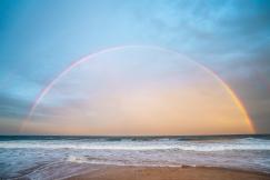 An illustrative photo of a rainbow over a rippling sea