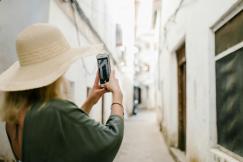 An illustrative photo of a woman taking a photo of a building in a narrow alley