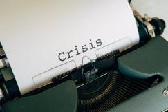 An illustrative photo of a vintage typewriter with a sheet of white paper inserted and word "Crysis" typed on it