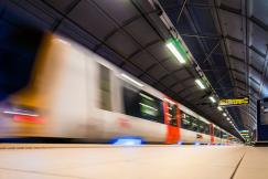 An illustrative photo of a beige and red train speeding along the tracks