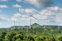 An illustrative photo of wind turbines on green grass field under white clouds