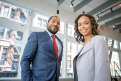 An illustrative photo of a man and a woman smiling inside an office building