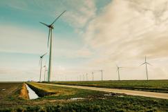 An illustrative photo of a windmill generating energy on a green grass field