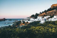 An illustrative photo of white buildings on mountain by the sea.