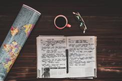 An illustrative photo of a map and a notebook on the wooden table