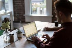 An illustrative photo of a man working on a laptop on a table