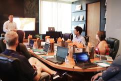 An illustrative photo of a person presenting to other people sitting with laptops