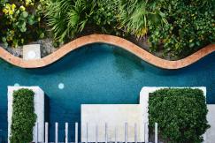 An illustrative photo of a swimming pool near a white concrete building