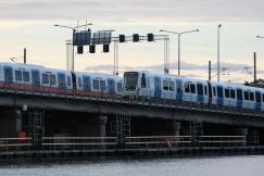 An illustrative photo of a blue and white train driving over a bridge