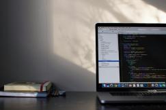 An illustrative photo of a laptop on a table with programming language on its screen