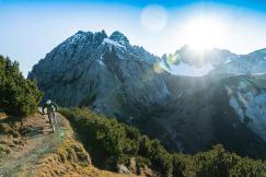 An illustrative photo of a person riding a bike on a trail in front of a mountain