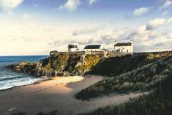 An illustrative photo of three white concrete houses on sea cliff.