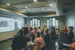 An illustrative photo of a group of people in a room with a projector screen