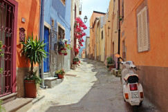 An illustrative photo of a white scooter near a building on a narrow street