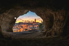 An illustrative photo of a brown cave with over view of city.