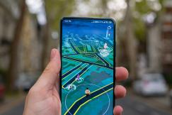 An illustrative photo of a person holding black smartphone with a game in it