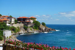 An illustrative photo of houses on a hill near a body of water.