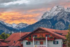 An illustrative photo of a house near snow covered mountain.