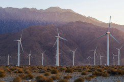 An illustrative photo of windmills in the desert with mountains in the background