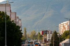 An illustrative photo of a road with many cars with mountains in the background