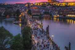An illustrative photo of people walking on the bridge in Prague during nighttime
