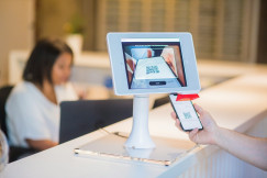 An illustrative photo of a person scanning a QR-code at the reception desk