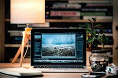 An illustrative photo of a laptop on a wooden table beside a lamp