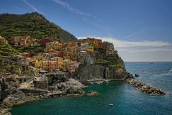 An illustrative photo of houses on a hill near a body of water.