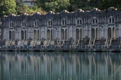 An illustrative photo of a gray concrete building reflection on a body of water
