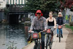An illustrative photo of three people riding bicycles near a body of water in the city