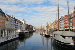 An illustrative photo of several boats docked in the water next to a row of buildings.