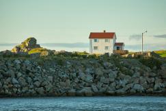 An illustrative photo of a house on a rocky hill by the water.