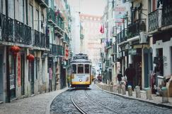 An illustrative photo of a train passing in between buildings in Lisbon