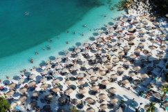 An illustrative photo of a beach with umbrellas full of people