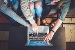 An illustrative photo of three people working together on one laptop