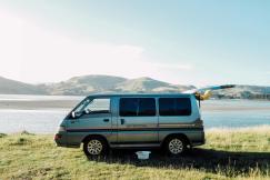 An illustrative photo of a silver van parked on green grass field.