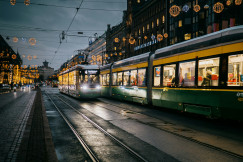 An illustrative photo of a green and white tram on the street in Finland during night time